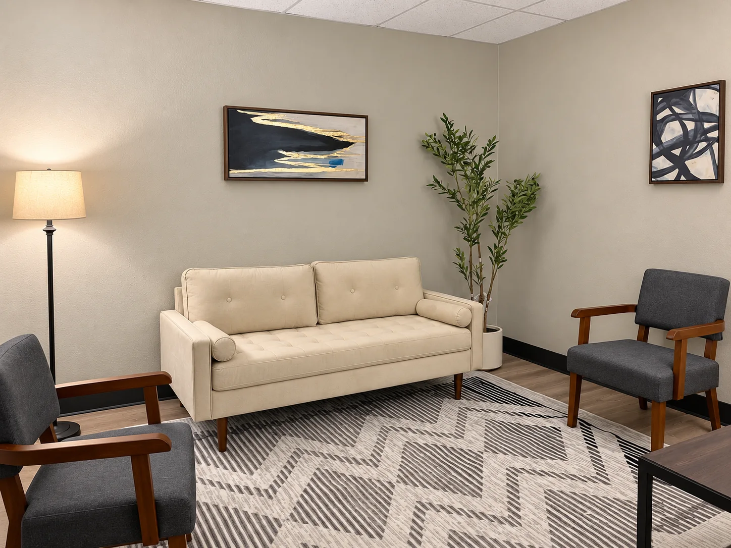 Therapy room with a cream sofa and two gray chairs